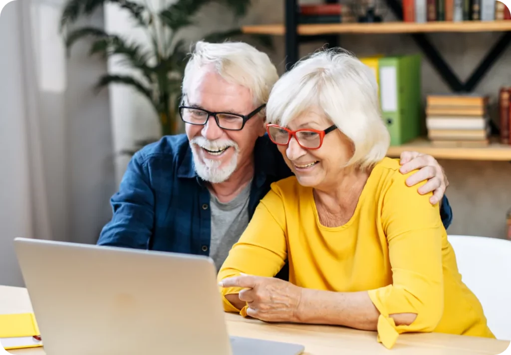 Senior couple sitting at desk and using Laptop at home